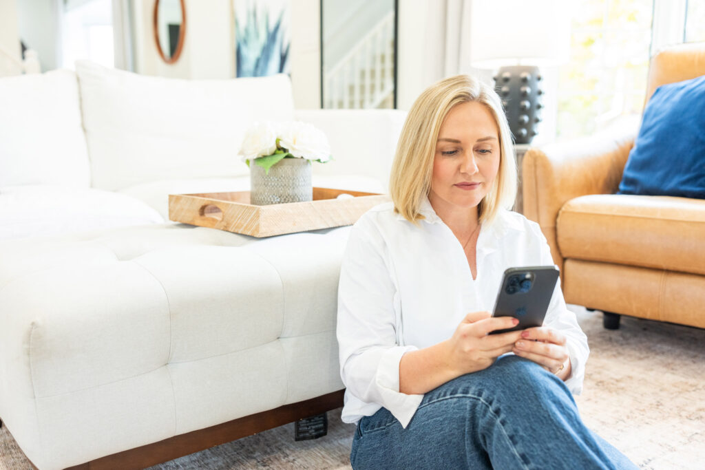 PEI Realtor Jessica Flemming sits on the floor on her phone contacting first time home buyers in PEI